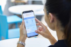 image of woman's side profile holding up her mobile phone using the mood tracker app